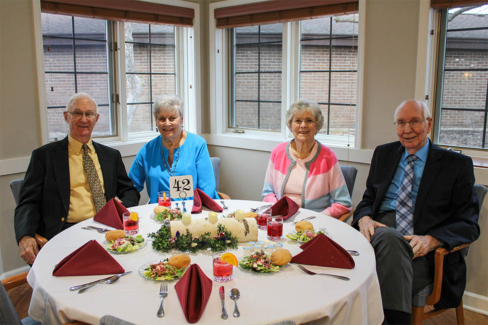 Two couples in formal clothes at a dinner table