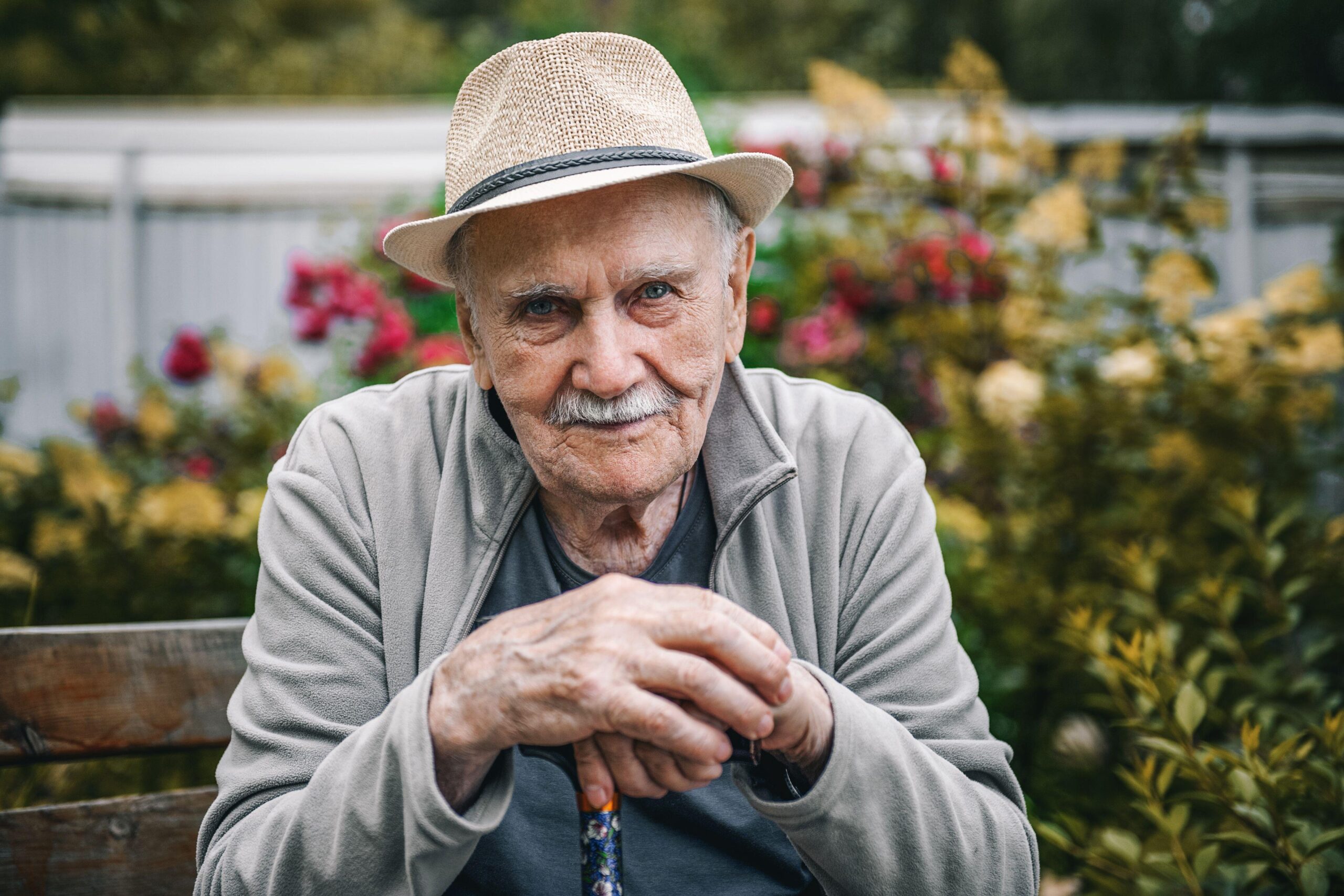 Portrait of a smiling and confident older 87-year-old handsome man in a hat with a mustache. Happy active old age. Portrait of a man in the autumn