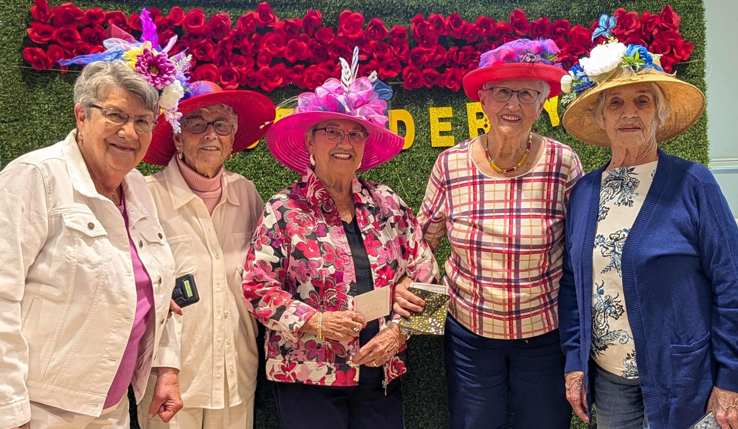 senior ladies with hats standing in front of a grass background
